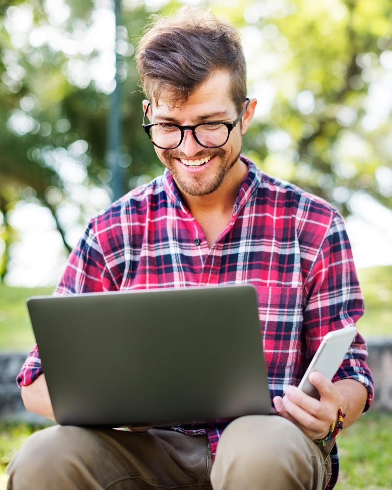 young-man-smartphone-browsing-laptop-concept-PL96PN7.jpg